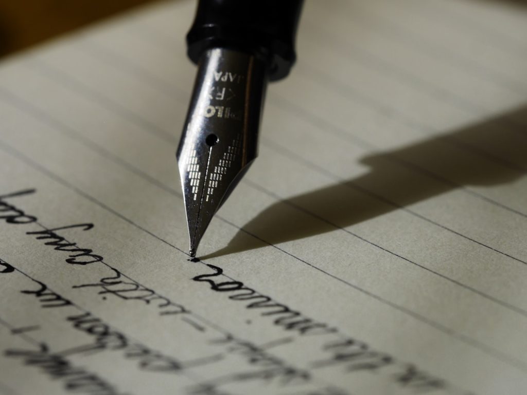 Student writing an essay in a notebook, representing IPMAT WAT preparation