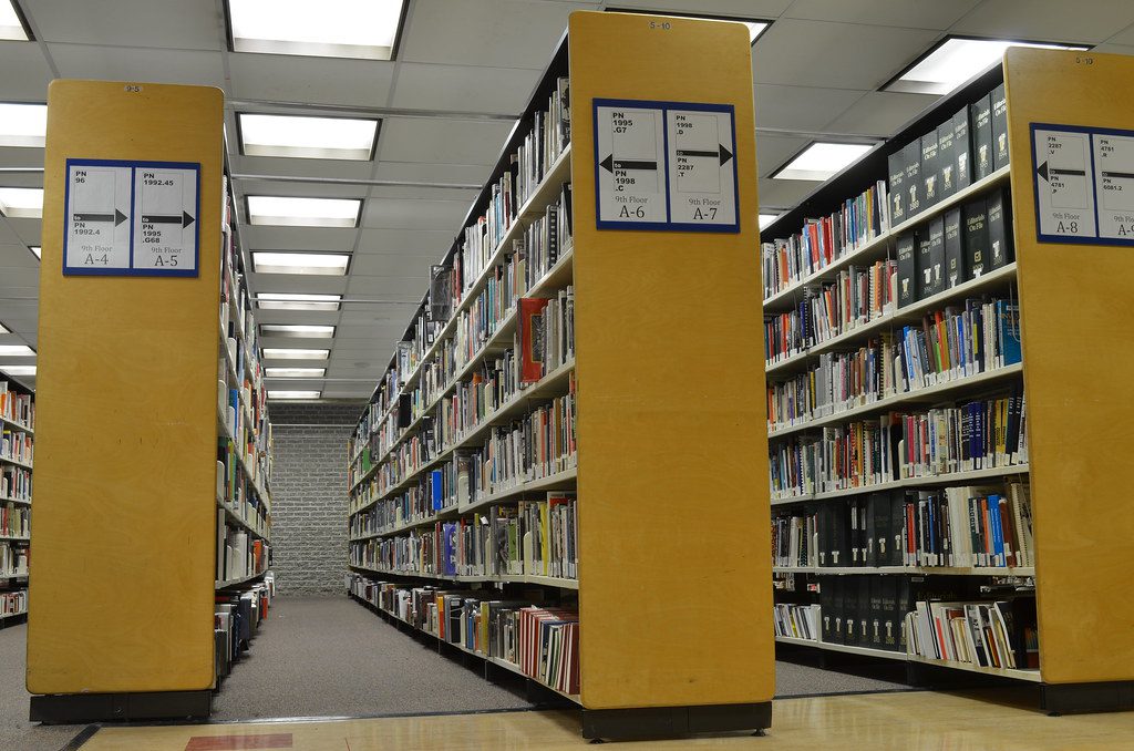 Rows of books on university library shelves